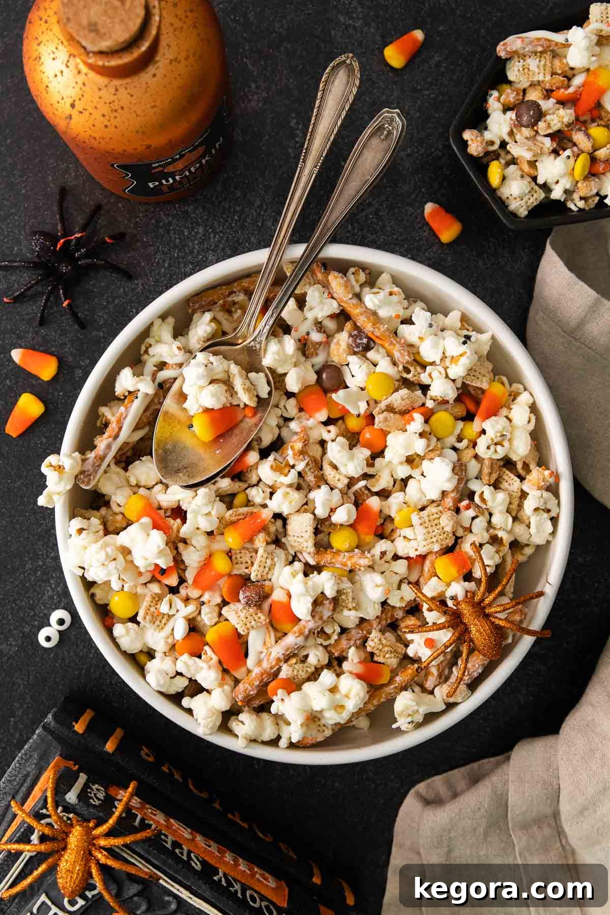 Monster Munch Mix 8 A bowl of Halloween snack mix sits on a festively decorated table with spooky themed elements.