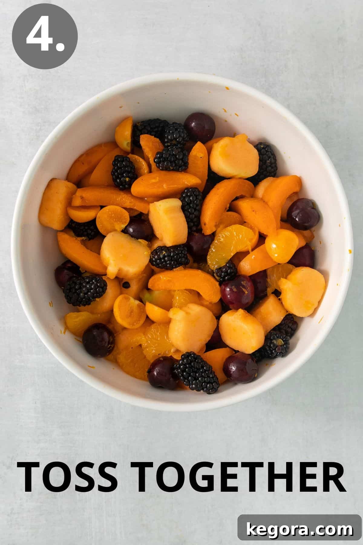Monster Mash Fruit Salad 7 The Halloween fruit salad fully tossed in a large bowl, glistening with the honey-orange dressing, showcasing its freshness and vibrant colors.