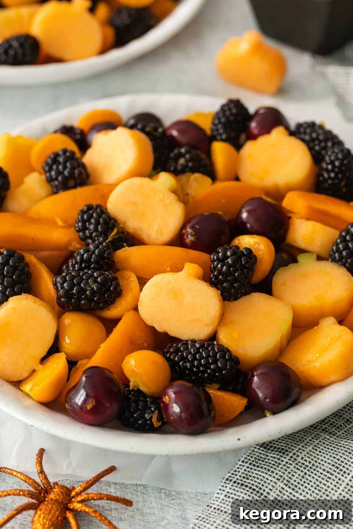 A close-up view of the Halloween fruit salad in a bowl, highlighting the intricate pumpkin shapes and the colorful blend of fruits.