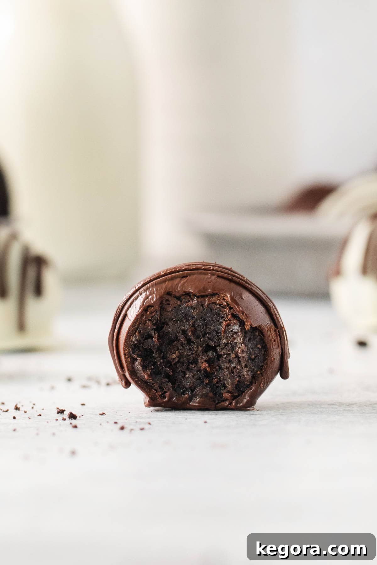 Gluten-Free Oreo Dream Bites 7 A single gluten-free Oreo truffle on a countertop, with a bite taken out, revealing its creamy center.
