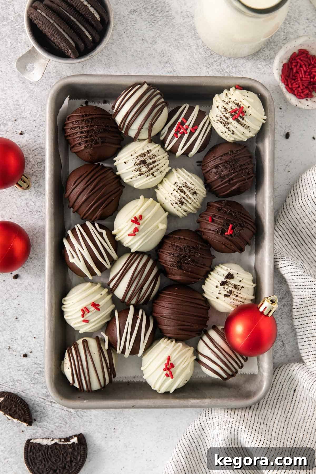 Gluten-Free Oreo Dream Bites 8 An overhead view of festive gluten-free Oreo truffles arranged on a baking sheet, surrounded by holiday ornaments.