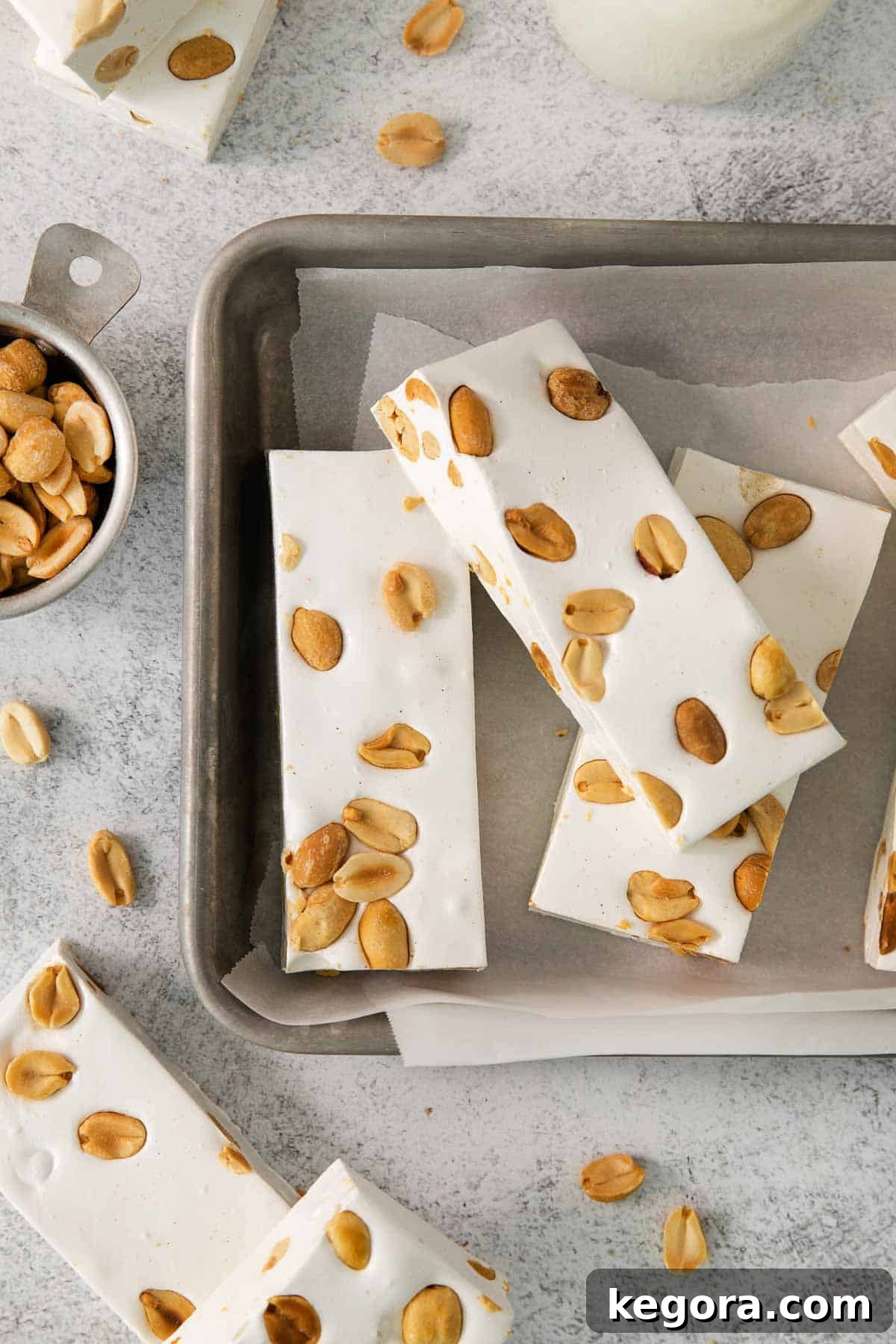 Crafting Irresistible Nougat 2 Sliced homemade nougat recipe with peanuts on a parchment-lined baking sheet, ready to be enjoyed.