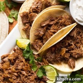 Perfect Instant Pot Mini Pork Carnitas 4 Pork Carnitas in small tortillas on a white platter garnished with lime and cilantro