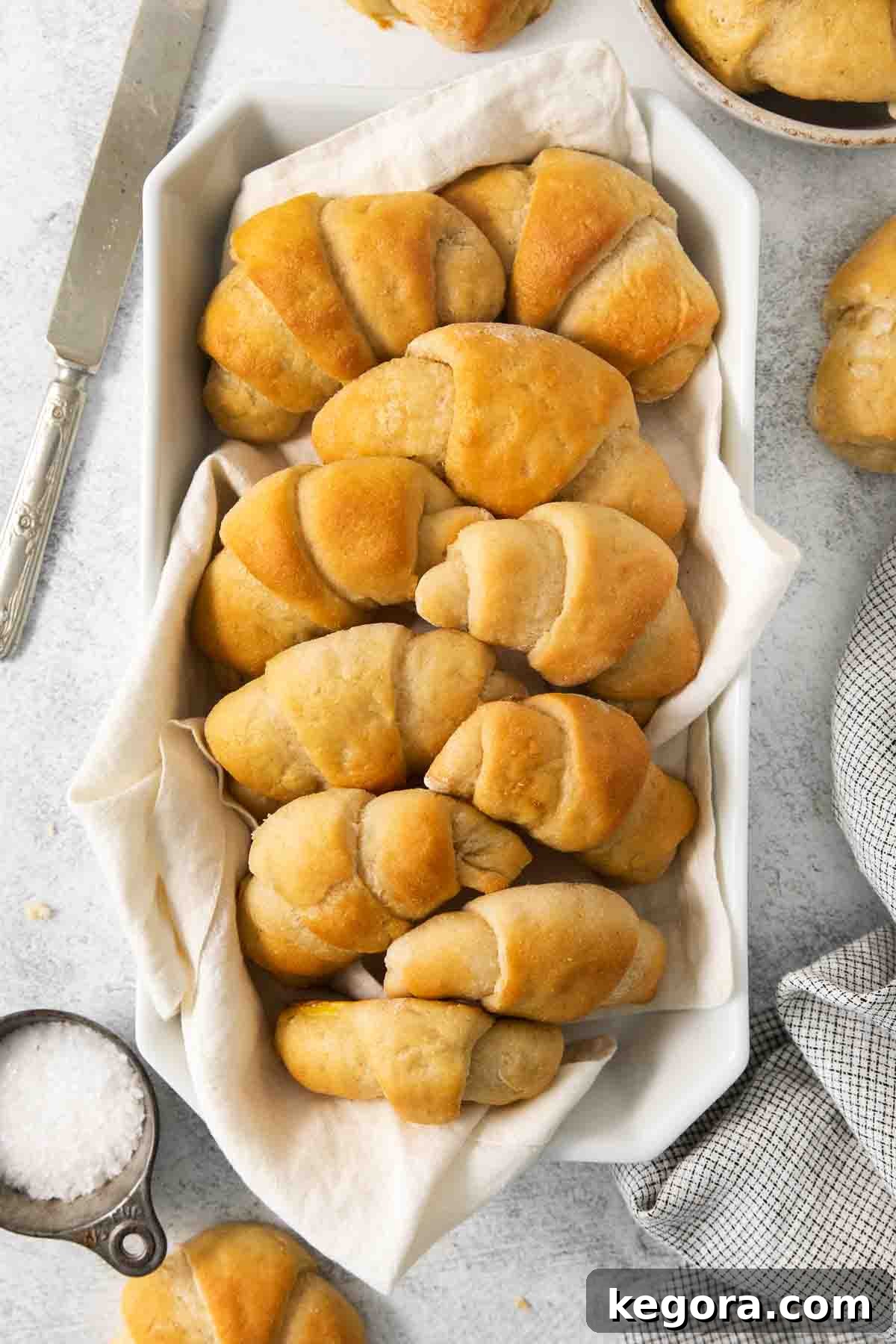 Scrumptious Gluten Free Crescent Rolls 14 A rustic bowl overflowing with warm, golden-brown gluten-free crescent rolls, with a cozy towel folded beside it.