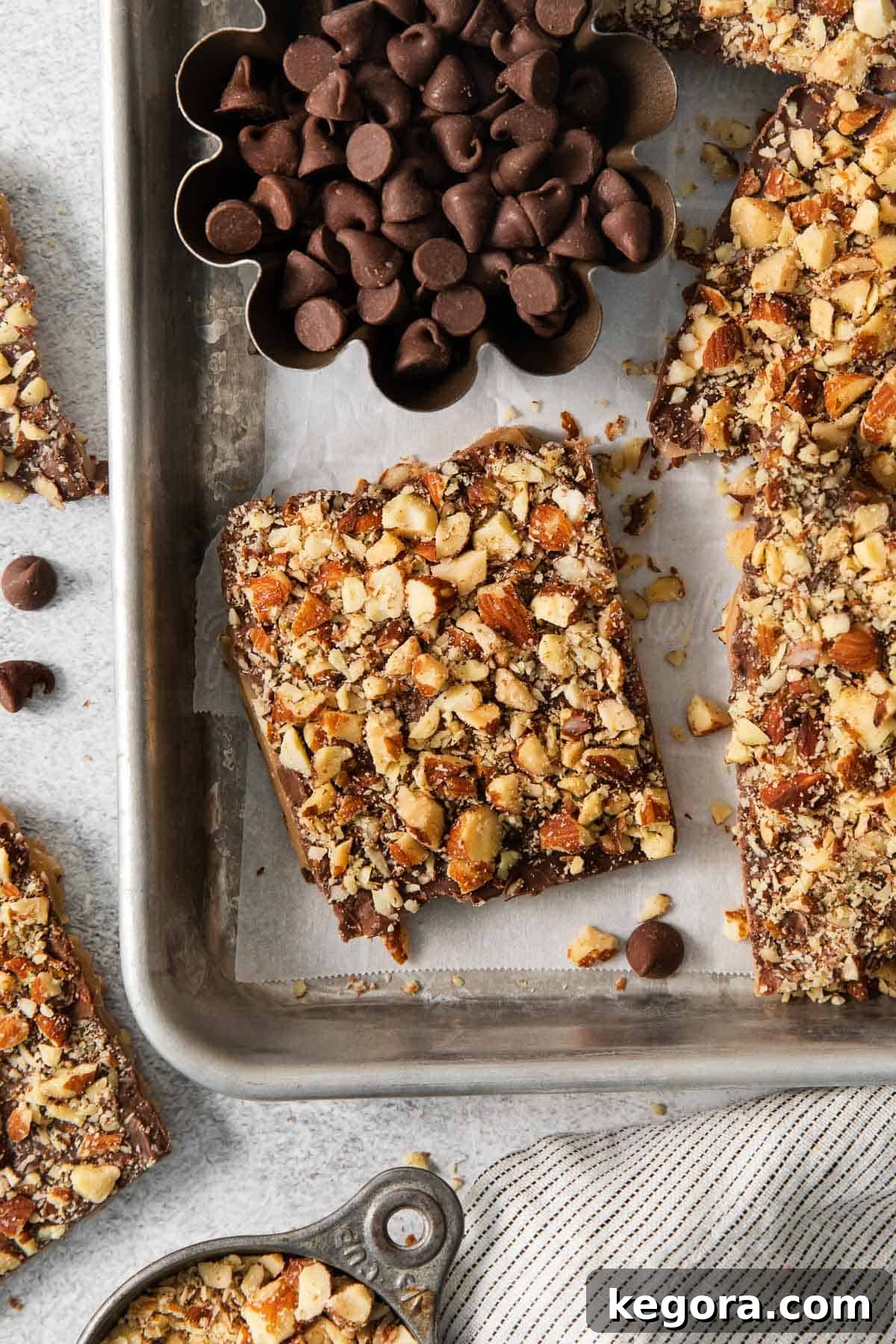 Close-up of English toffee pieces, adorned with chocolate and nuts, elegantly arranged in a baking sheet.