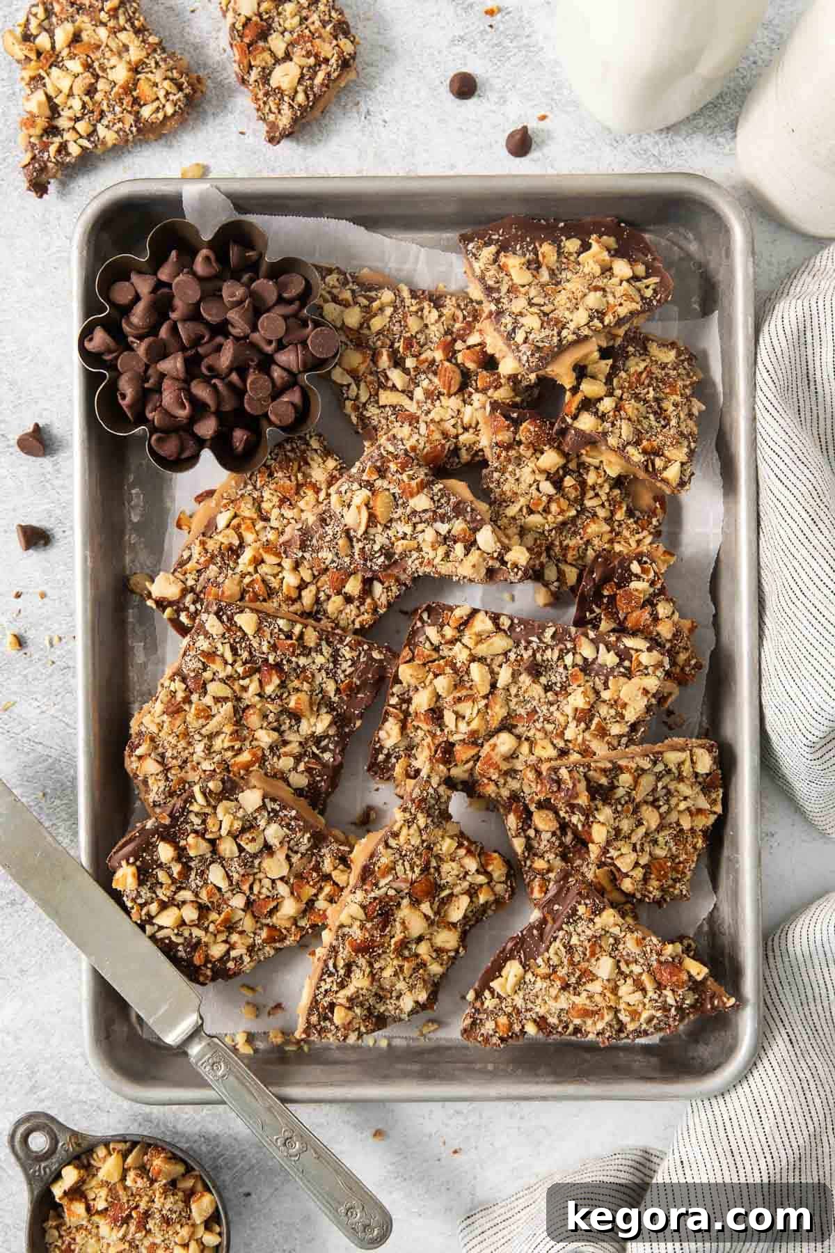 English toffee slab cooling on a baking sheet lined with parchment paper, awaiting chocolate and nuts.