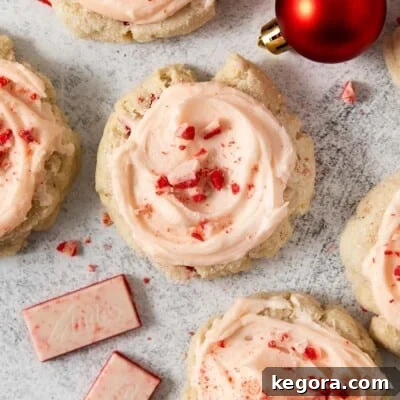 Gluten-free peppermint sour cream sugar cookies arranged on a festive countertop with holiday ornaments and white chocolate peppermint pieces, showcasing their vibrant colors and appealing texture.