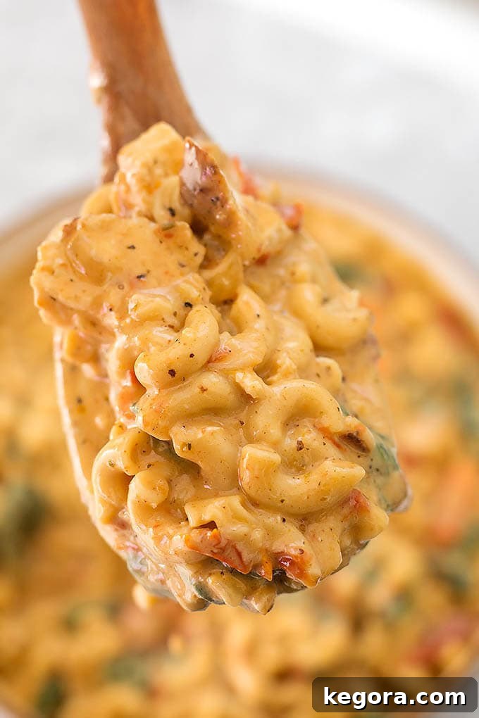 Close up of Creamy Garlic Tuscan Chicken Pasta on a wooden serving spoon