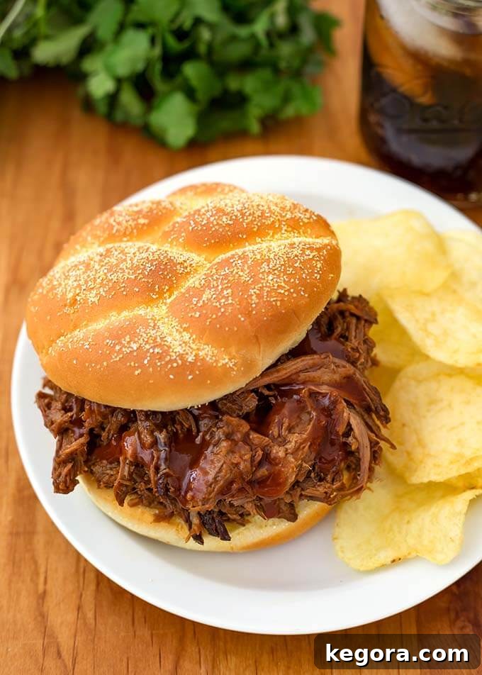 15 Instant Pot Hacks for Effortless Cooking 4 Instant Pot Barbecue Beef on a hamburger bun with potato chips on a white plate