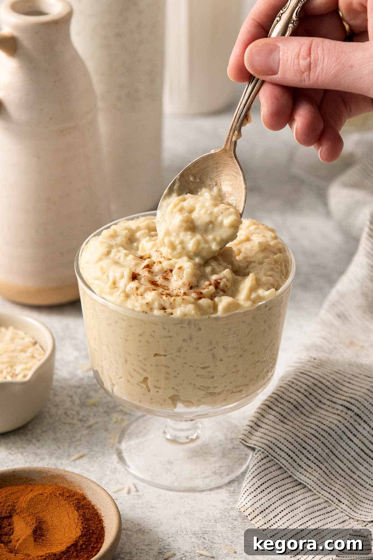 dairy-free rice pudding in a glass far, with a spoon dipping into the jar.