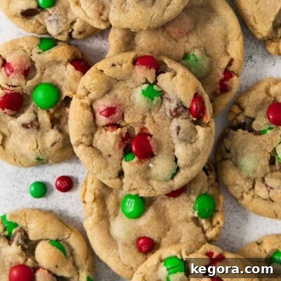 A cluster of freshly baked gluten-free M&M cookies on a piece of parchment paper, highlighting their perfect golden edges and colorful candy inclusions.