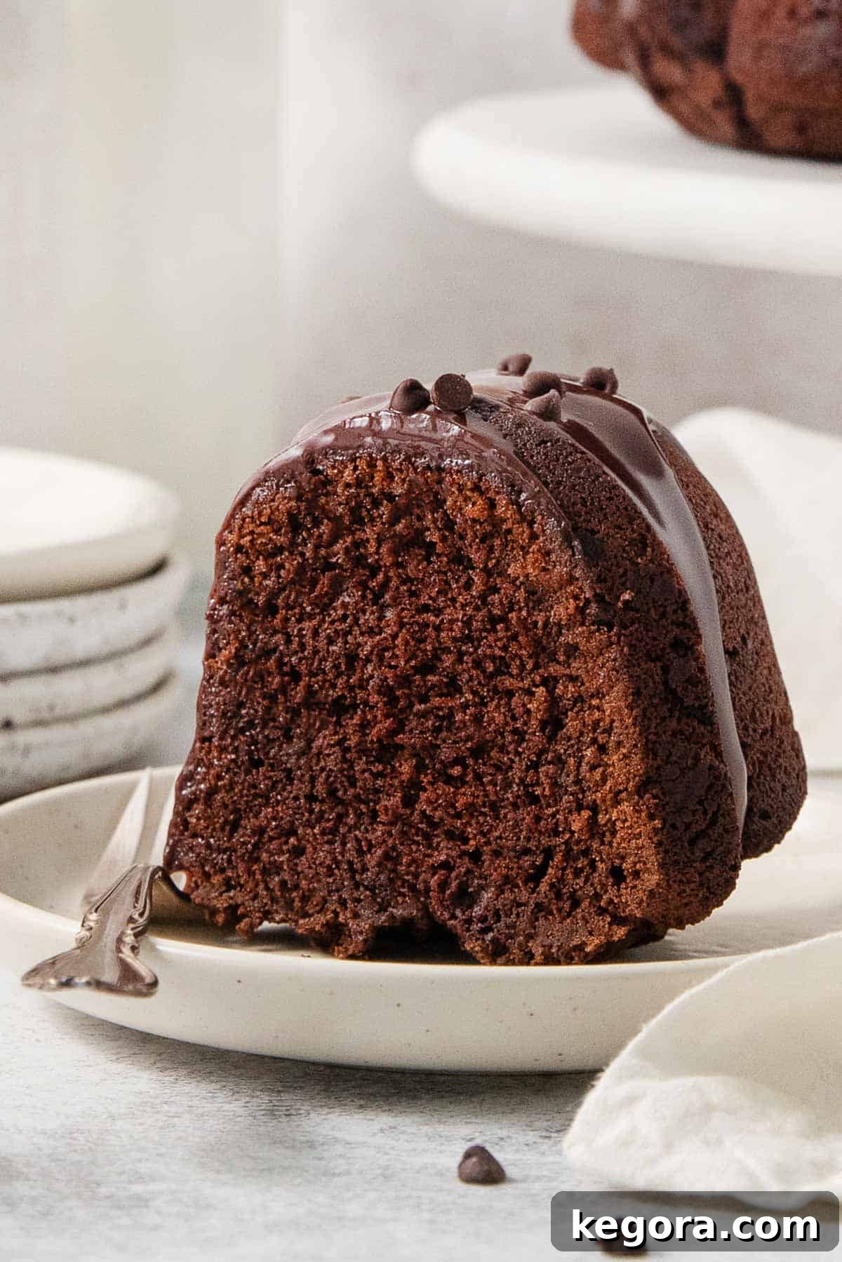 Decadent Gluten-Free Chocolate Bundt Cake 7 A perfectly sliced piece of gluten-free chocolate bundt cake on a white plate with a fork