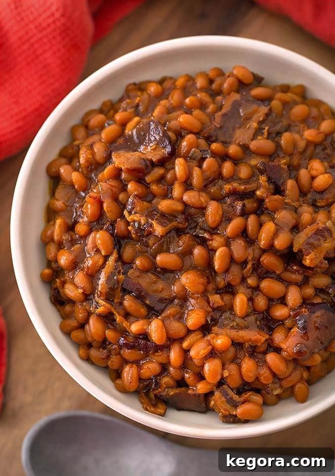 Soul-Satisfying Smoky Sweet Instant Pot Beans 2 Delicious Smoky Sweet Baked Beans served in a white bowl on a rustic wooden board, ready to be enjoyed.