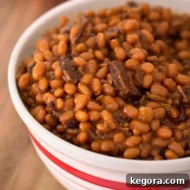 Soul-Satisfying Smoky Sweet Instant Pot Beans 5 Close-up view of Instant Pot Smoky Sweet Baked Beans in a round white bowl, beautifully presented on a wooden surface.