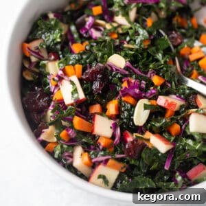 Close up shot of a vibrant kale salad in a white bowl with a serving spoon, enticingly fresh.