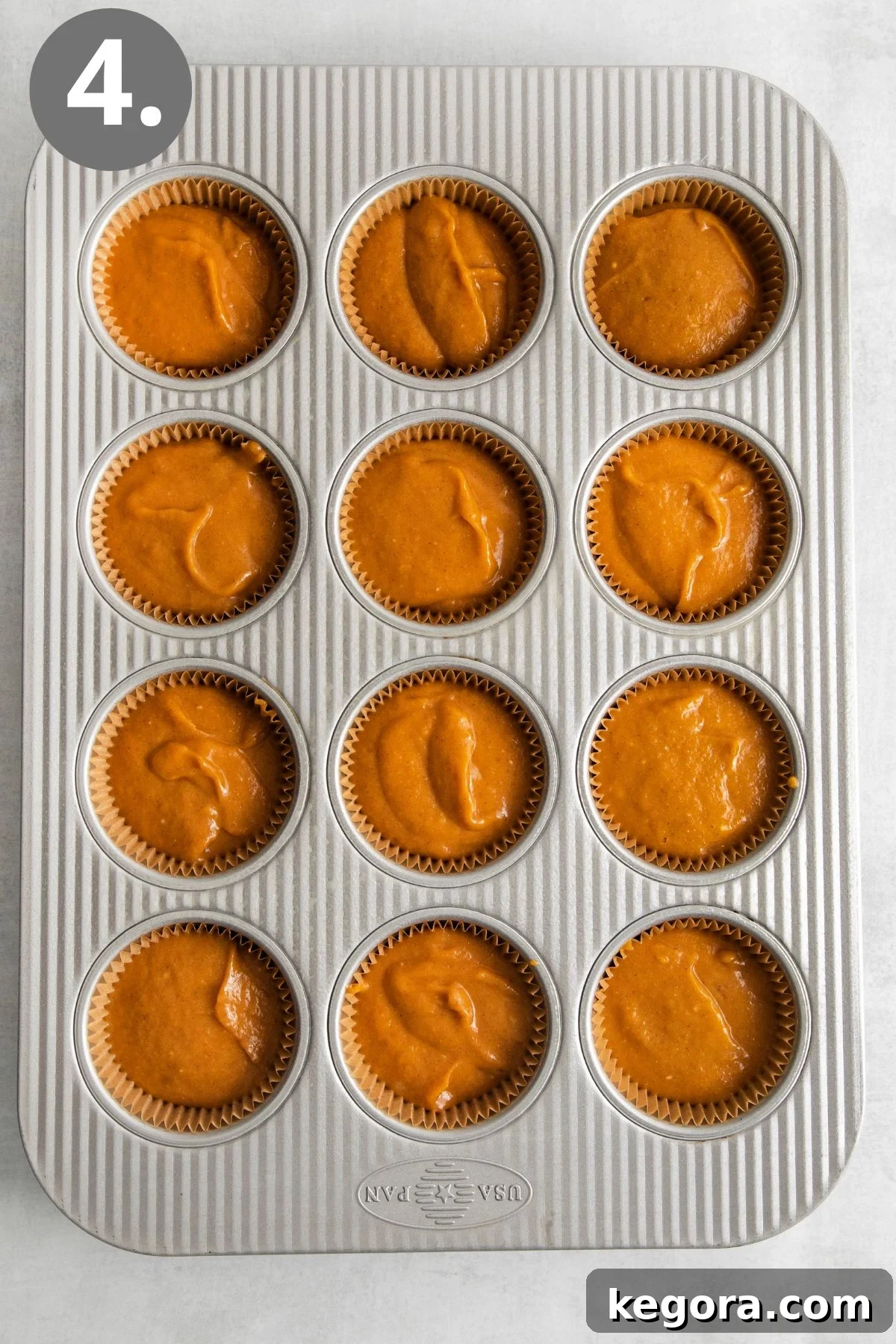 A muffin pan neatly filled with the rich orange pumpkin pie batter, ready to be placed in the oven for baking.