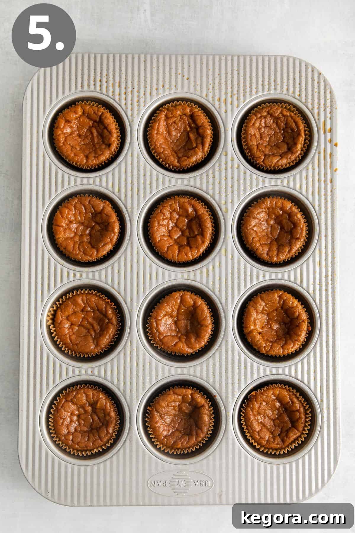 Freshly baked crustless pumpkin pie cupcakes, still warm in the muffin pan, displaying their slightly sunken centers – a perfectly normal outcome.
