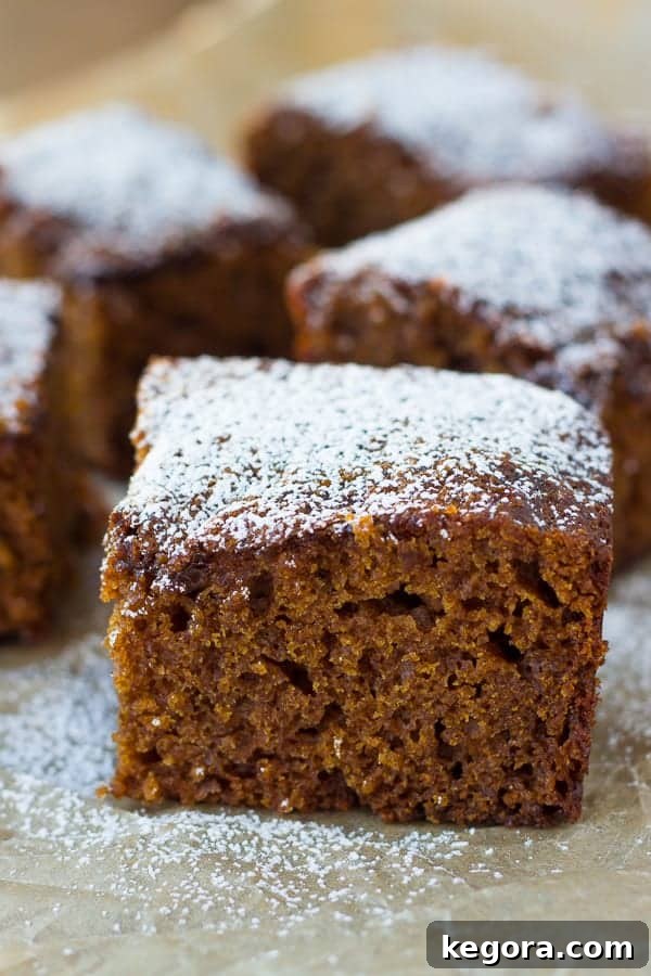Gluten-Free Gingerbread Cake A delectable slice of gingerbread cake, elegantly dusted with powdered sugar, ready for a festive treat.