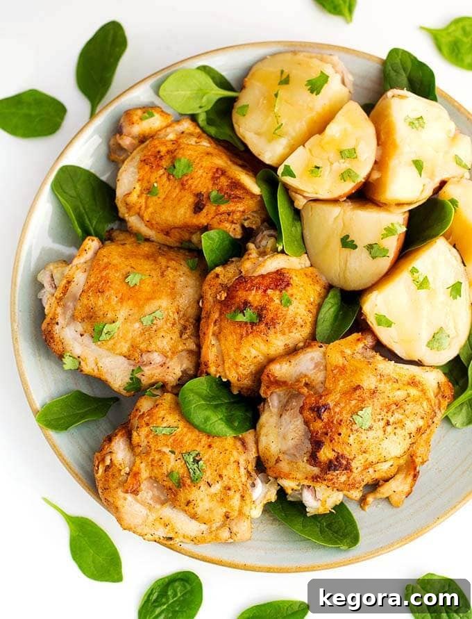 The Most Beloved Instant Pot Dishes of 2017 14 Juicy Instant Pot Chicken Thighs on a white plate, elegantly garnished with fresh baby spinach, offering a balanced and delicious meal.