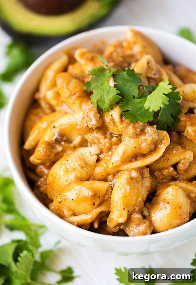 The Most Beloved Instant Pot Dishes of 2017 7 Instant Pot Cheesy Taco Pasta in a white bowl, generously garnished with fresh cilantro, showcasing its vibrant and appetizing look.