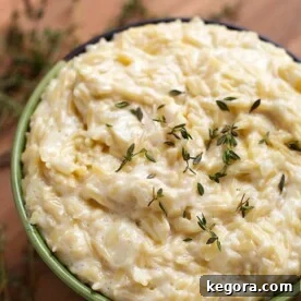 Cheesy Garlic Orzo pasta in a green bowl on a wooden board, showcasing the final delicious dish.