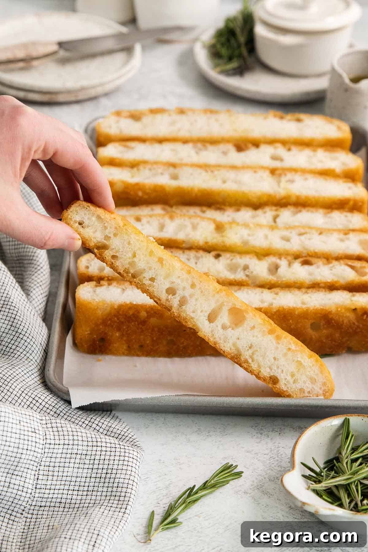 No Knead Overnight Gluten Free Focaccia with Caputo Flour 3 A golden-brown focaccia bread in a baking dish, with a slice being held up to show its airy interior.
