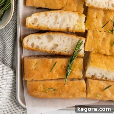Focaccia in a baking dish with fresh rosemary on top, ready to be served.