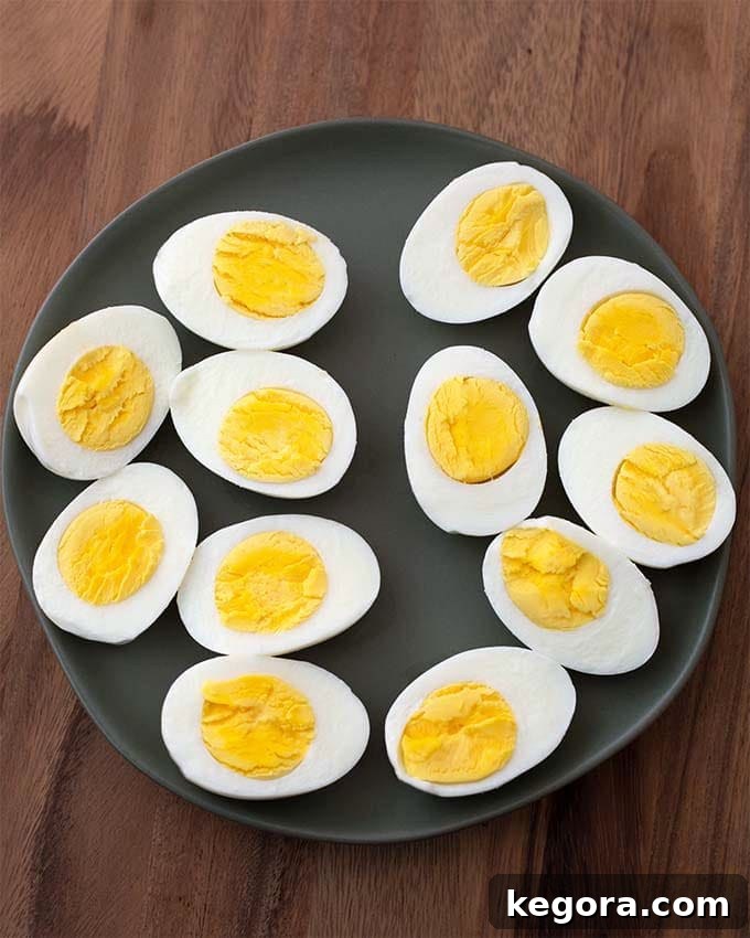 Instant Pot Boiled Eggs cut in half on black plate on wood board