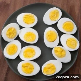 Boiled Eggs cut in half on black plate on wood board