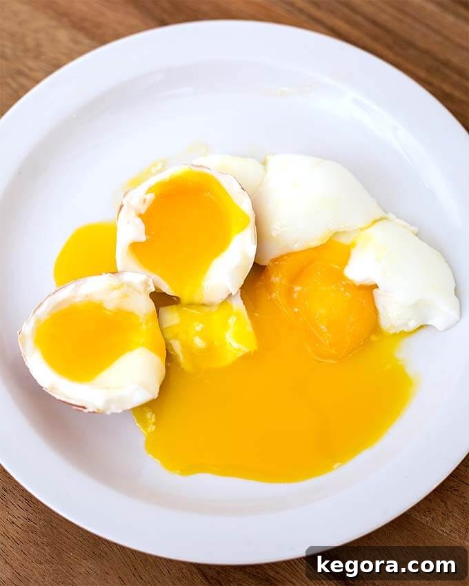Two soft Boiled Eggs cut in half on white plate on wooden board