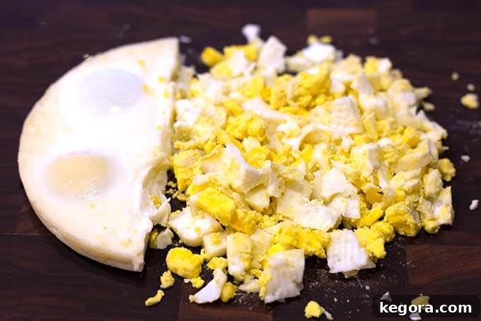 Egg loaf cut in half with one side crumbled to pieces on dark wood background