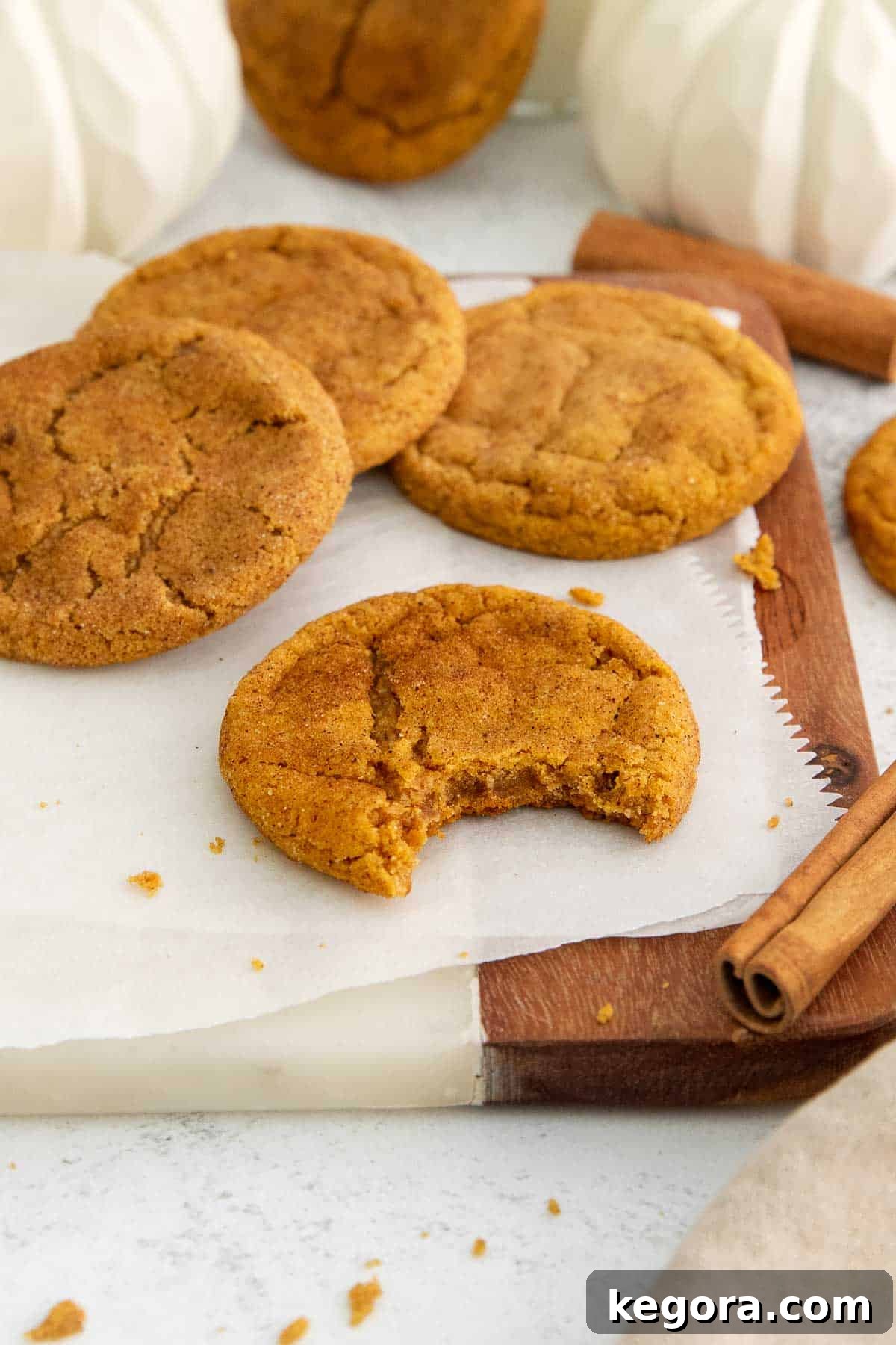 A stack of perfectly baked chewy gluten-free pumpkin snickerdoodles, golden brown with a delightful cinnamon-sugar coating, on a rustic countertop.