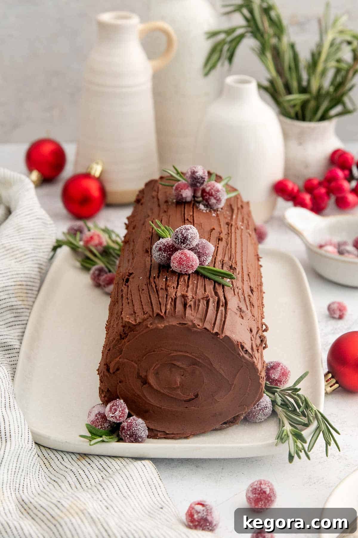 Gluten-Free Holiday Log Delight 3 A beautifully decorated gluten-free chocolate yule log, garnished with sugared cranberries and fresh rosemary, ready for the holidays.