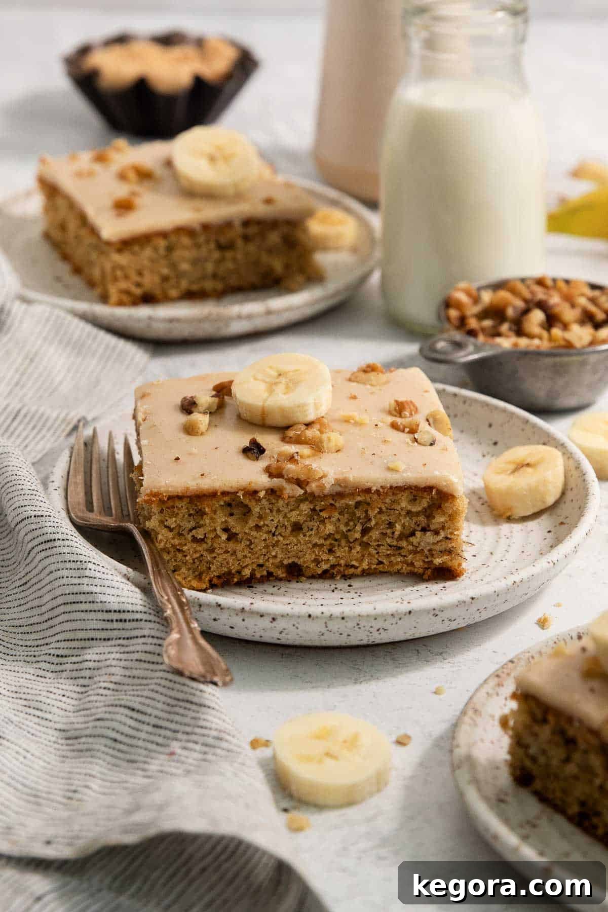 A gluten-free brown butter banana bar on a plate with a fork and banana slices on top