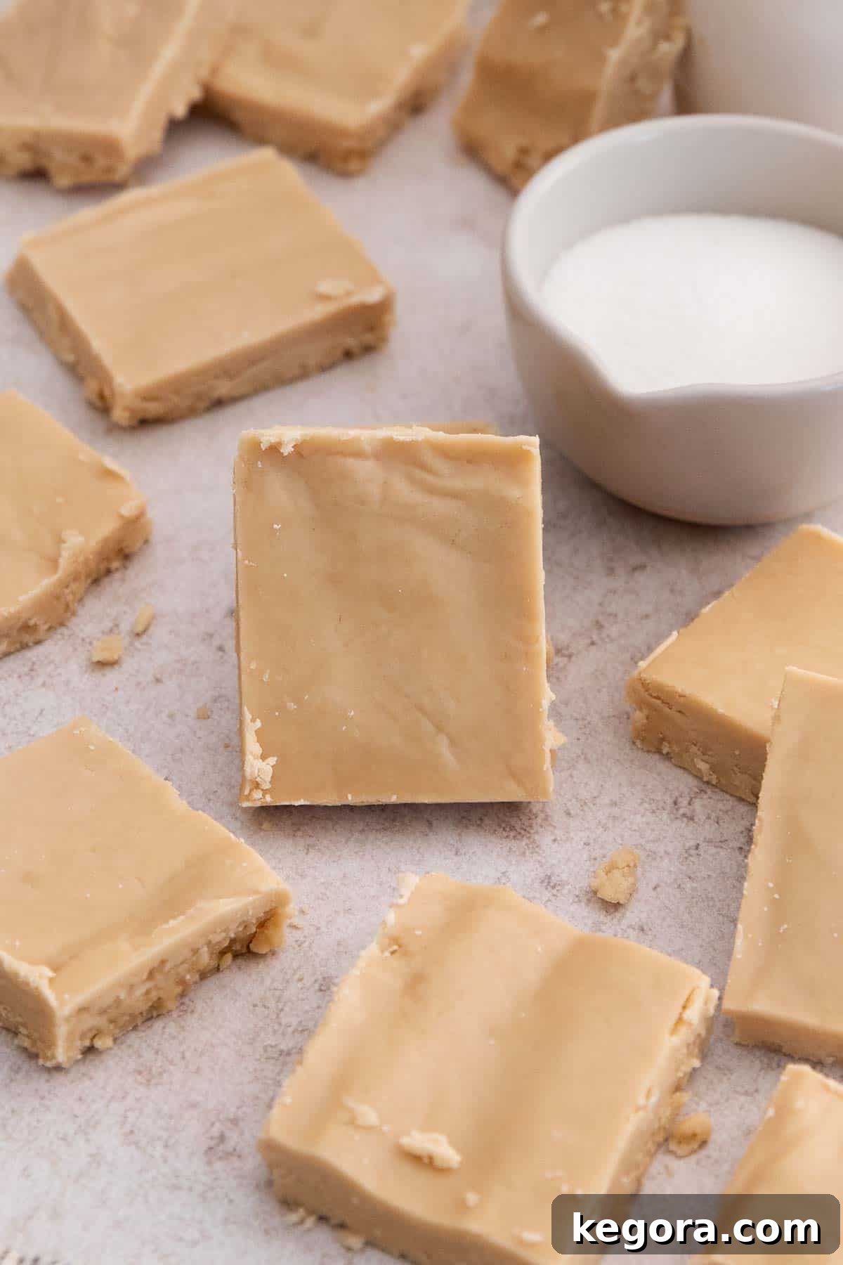 Golden Vanilla Penuche Fudge 8 Close-up of perfectly cut pieces of penuche vanilla fudge on a countertop, with one piece standing upright to highlight its creamy interior.