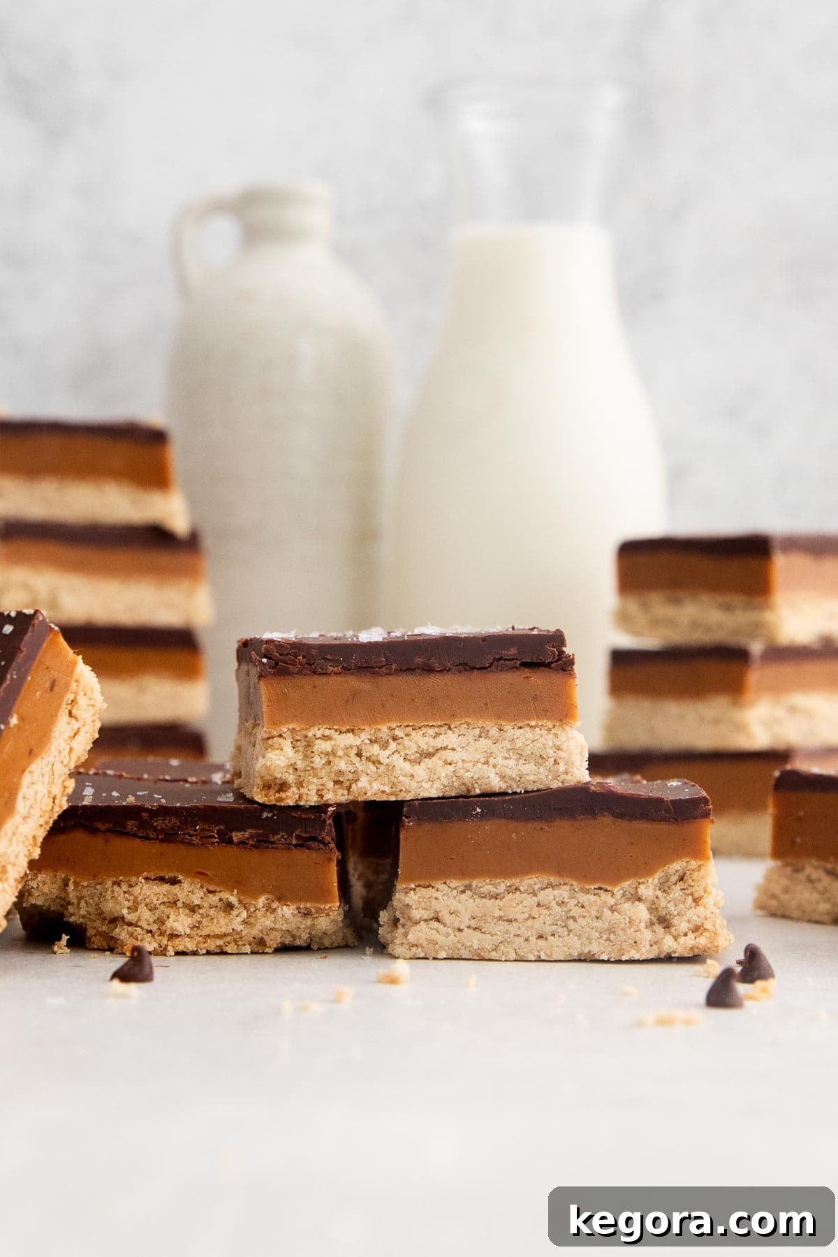 Gluten-free millionaire's shortbread bars stacked on a countertop, garnished with flaky salt