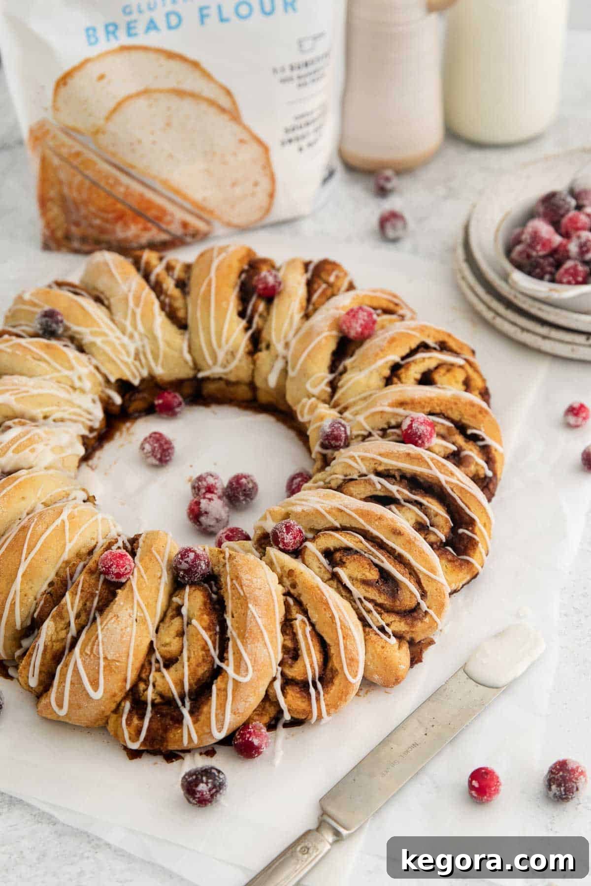 Irresistible Gluten-Free Cinnamon Swirl Wreath 10 A stunning top-down view of the freshly baked gluten-free cinnamon roll wreath, perfectly glazed and garnished with vibrant sugared cranberries, ready to be served.