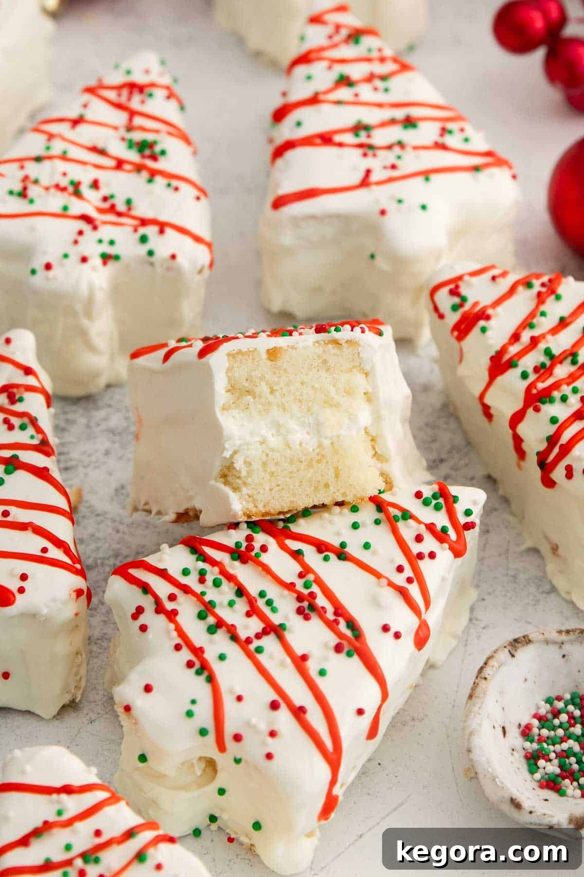 gluten-free little debbie christmas trees on a counter with a bite missing from one, beautifully decorated for the holidays.