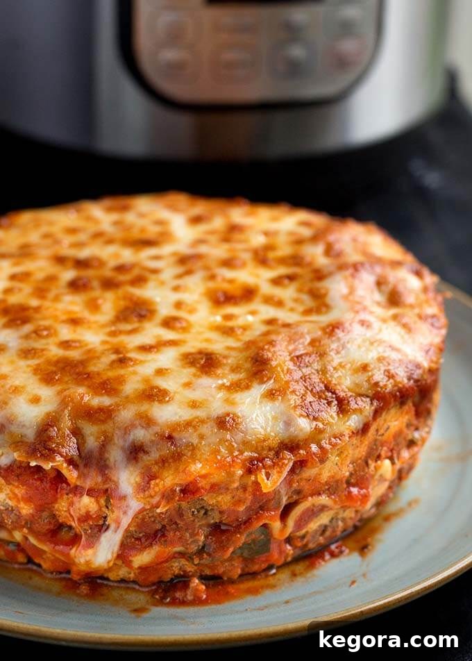 Whole round Lasagna on a light blue plate with pressure cooker in background
