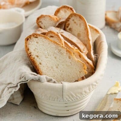 Slices of perfectly baked gluten-free artisan bread displayed in a bowl with a towel, highlighting its appealing crumb and readiness to serve.