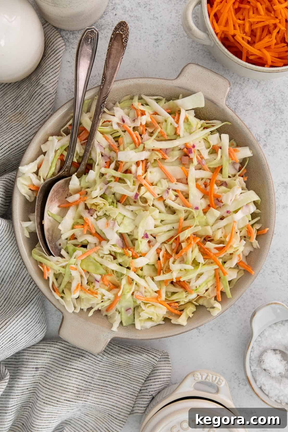 A large bowl of creamy dairy-free coleslaw with two serving spoons, ready to be enjoyed.