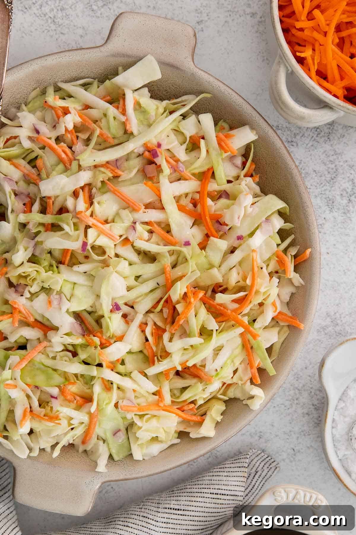 A vibrant bowl of dairy-free coleslaw, garnished with fresh herbs, ready to be served.