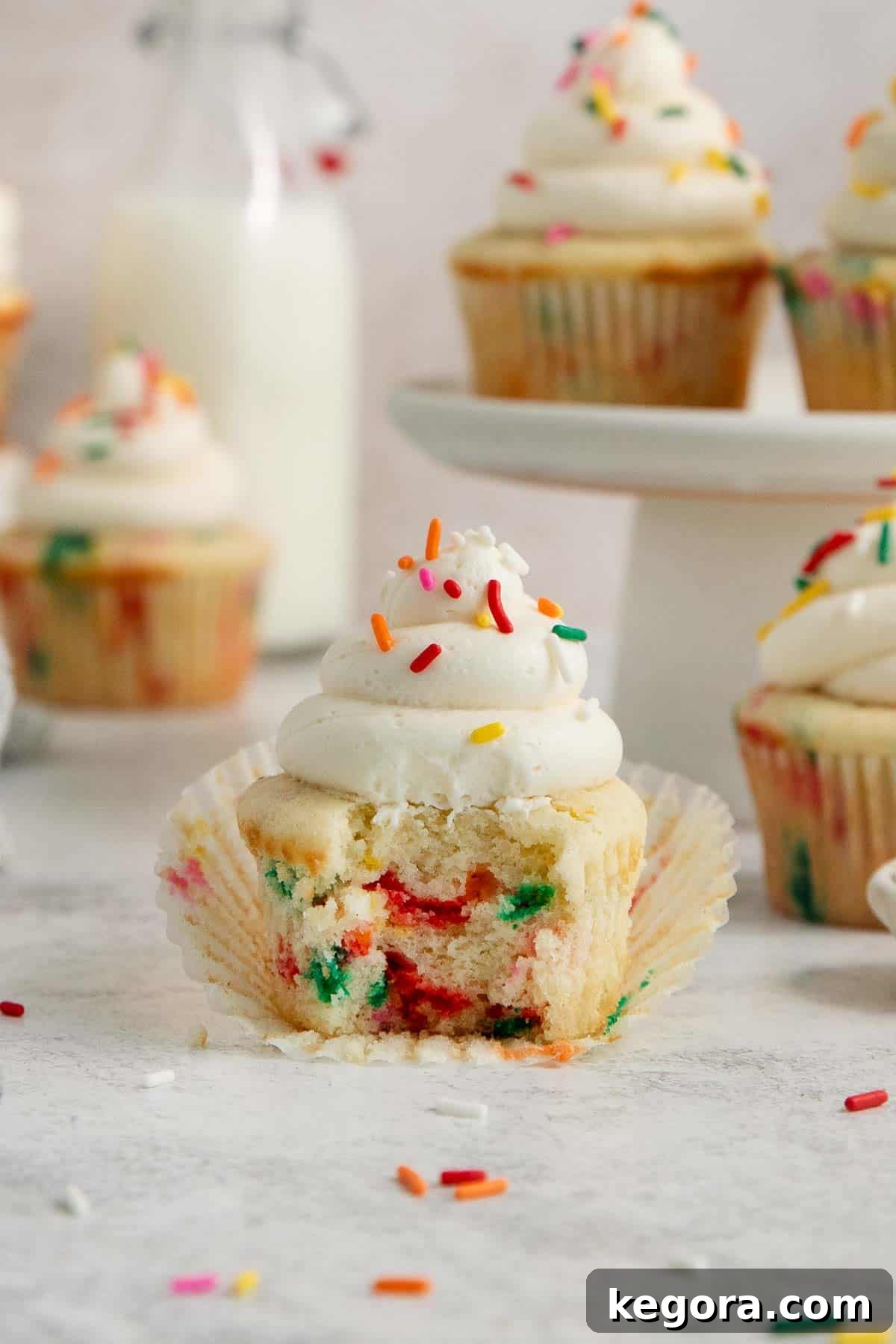 A funfetti cupcake with a bite taken out, showing the moist crumb and sprinkles inside.