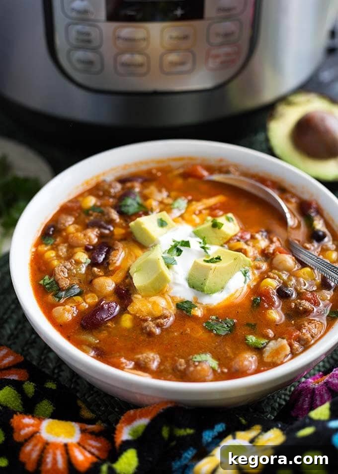 Taco Soup in a white bowl with silver spoon with pressure cooker in background