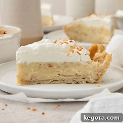 Gluten-Free Coconut Cloud Pie 11 A slice of gluten-free coconut cream pie on a white plate, ready to be enjoyed.