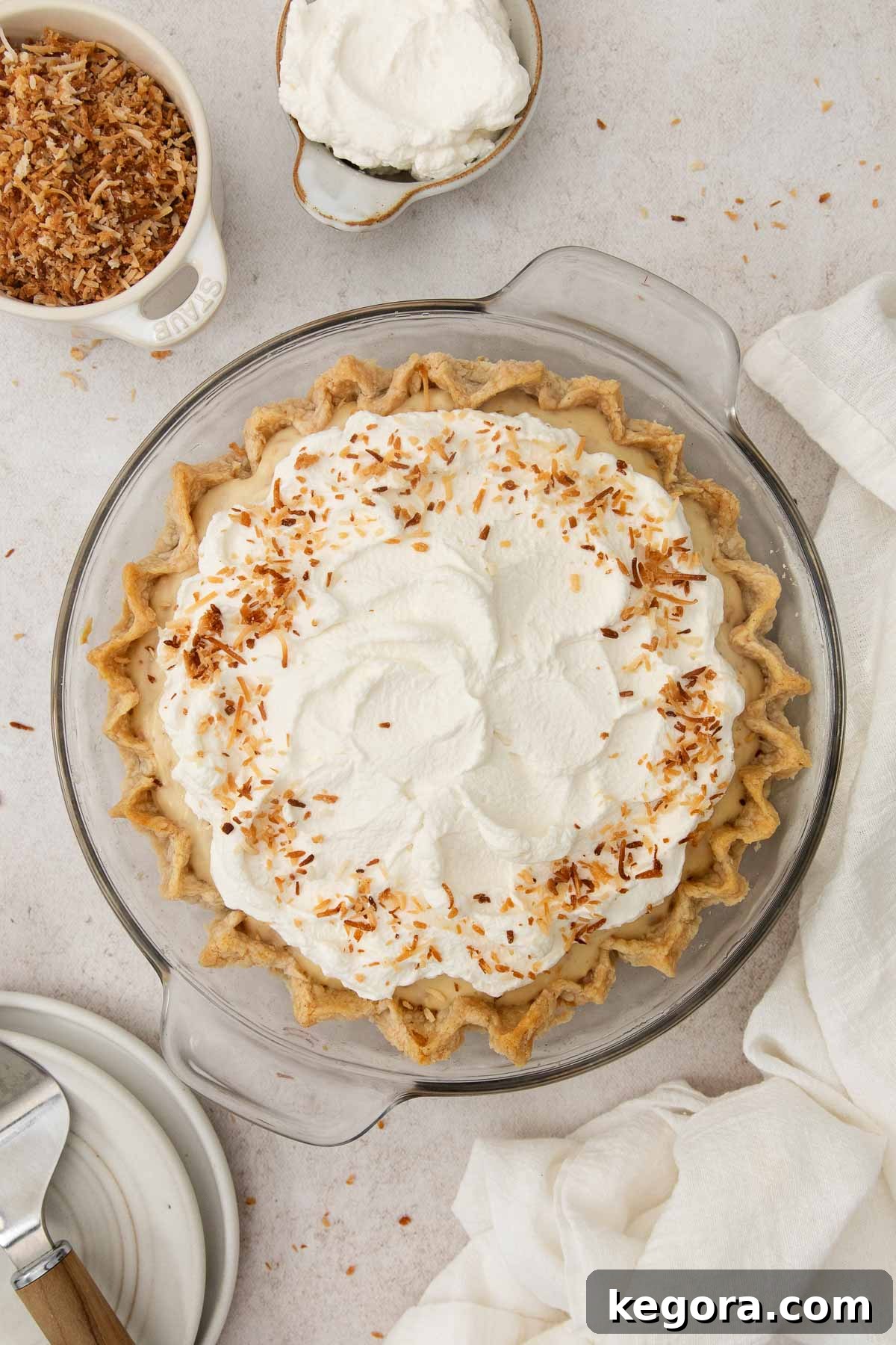 Gluten-Free Coconut Cloud Pie 3 Aerial view of a luscious gluten-free coconut cream pie in a glass dish, garnished with toasted coconut flakes.