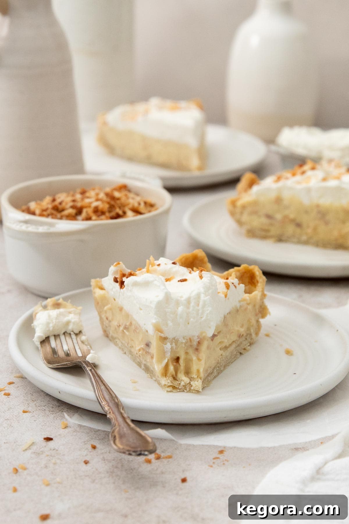Gluten-Free Coconut Cloud Pie 10 A perfectly plated slice of gluten-free coconut cream pie with a bite taken, showing the creamy filling and flaky crust.