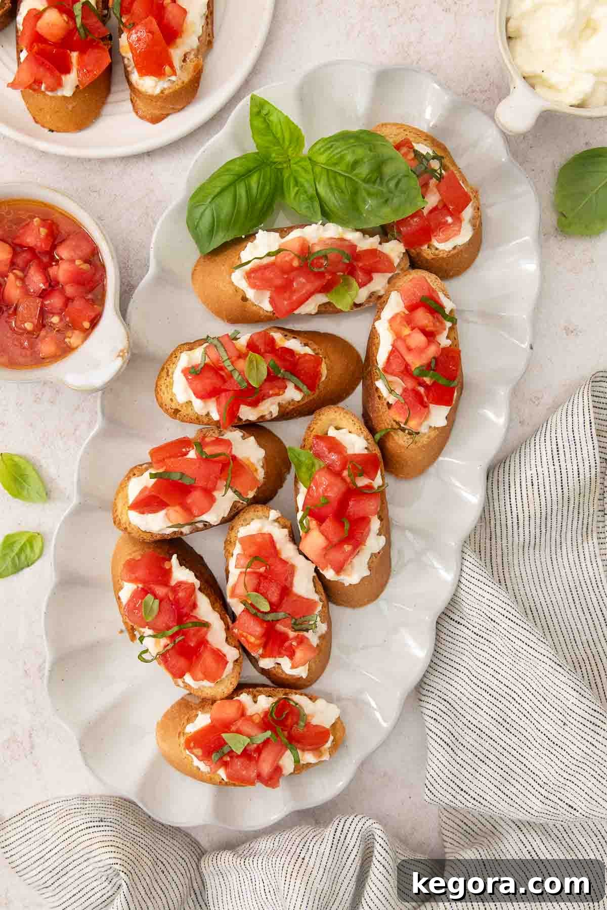 Gluten Free Bruschetta Bliss 3 Gluten-free bruschetta laid on a platter, with basil leaves garnishing the plate and scattered on the table.