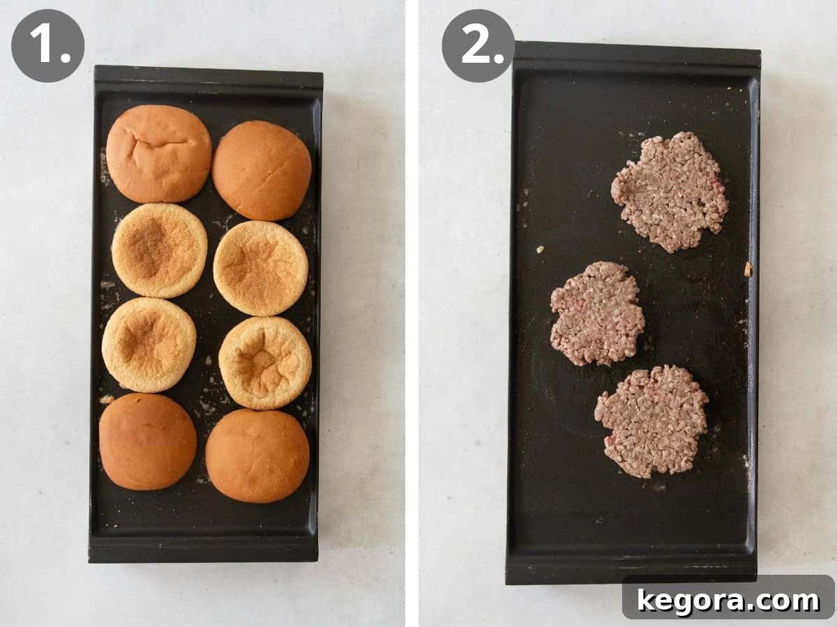 The initial steps of making smashburgers: gluten-free buns being toasted golden on a hot griddle, and loose balls of ground beef being placed onto the griddle, ready to be smashed.