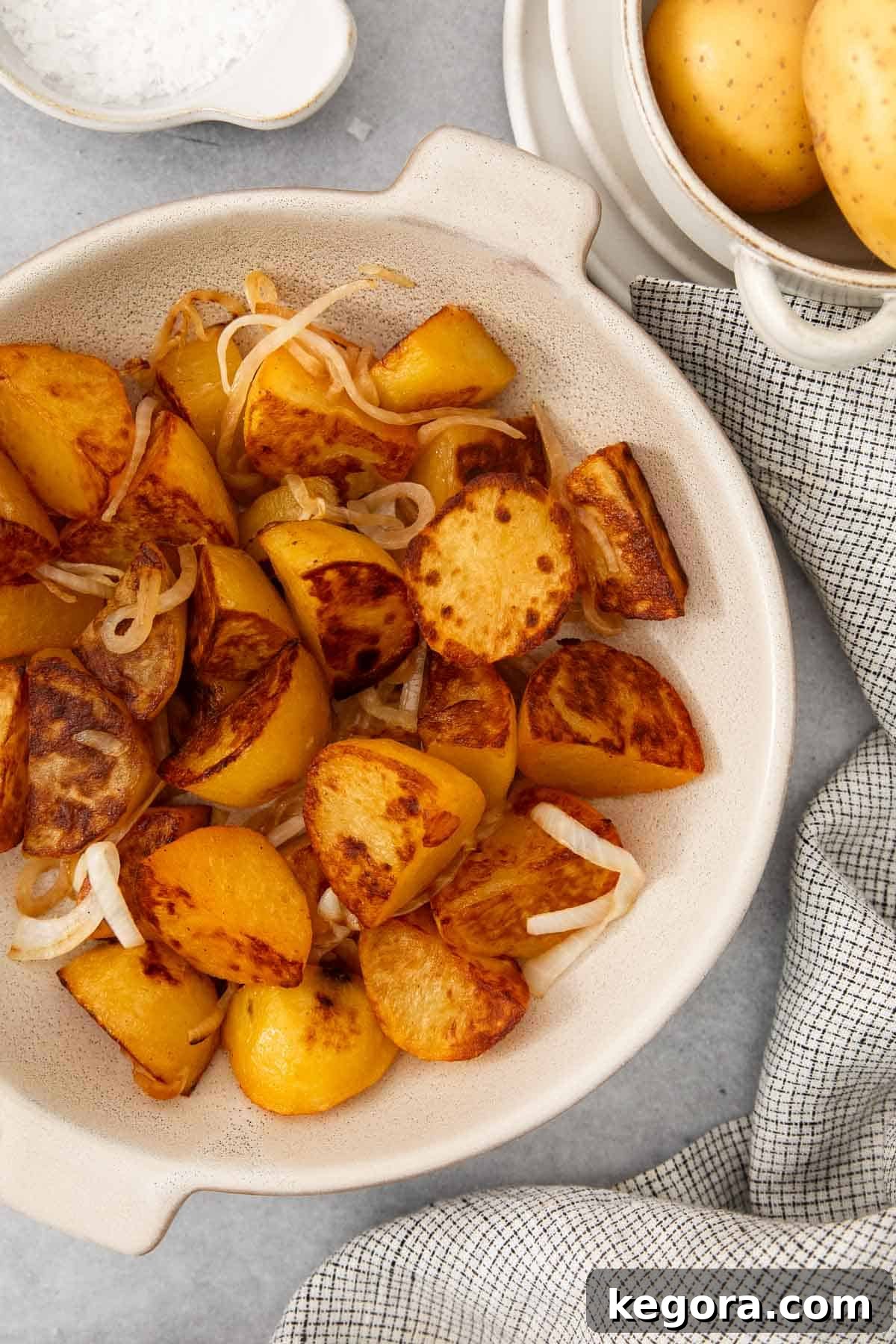 Blackstone Crispy Potatoes 3 A white bowl filled with perfectly crispy Blackstone fried potatoes and golden caramelized onions, ready to be served.